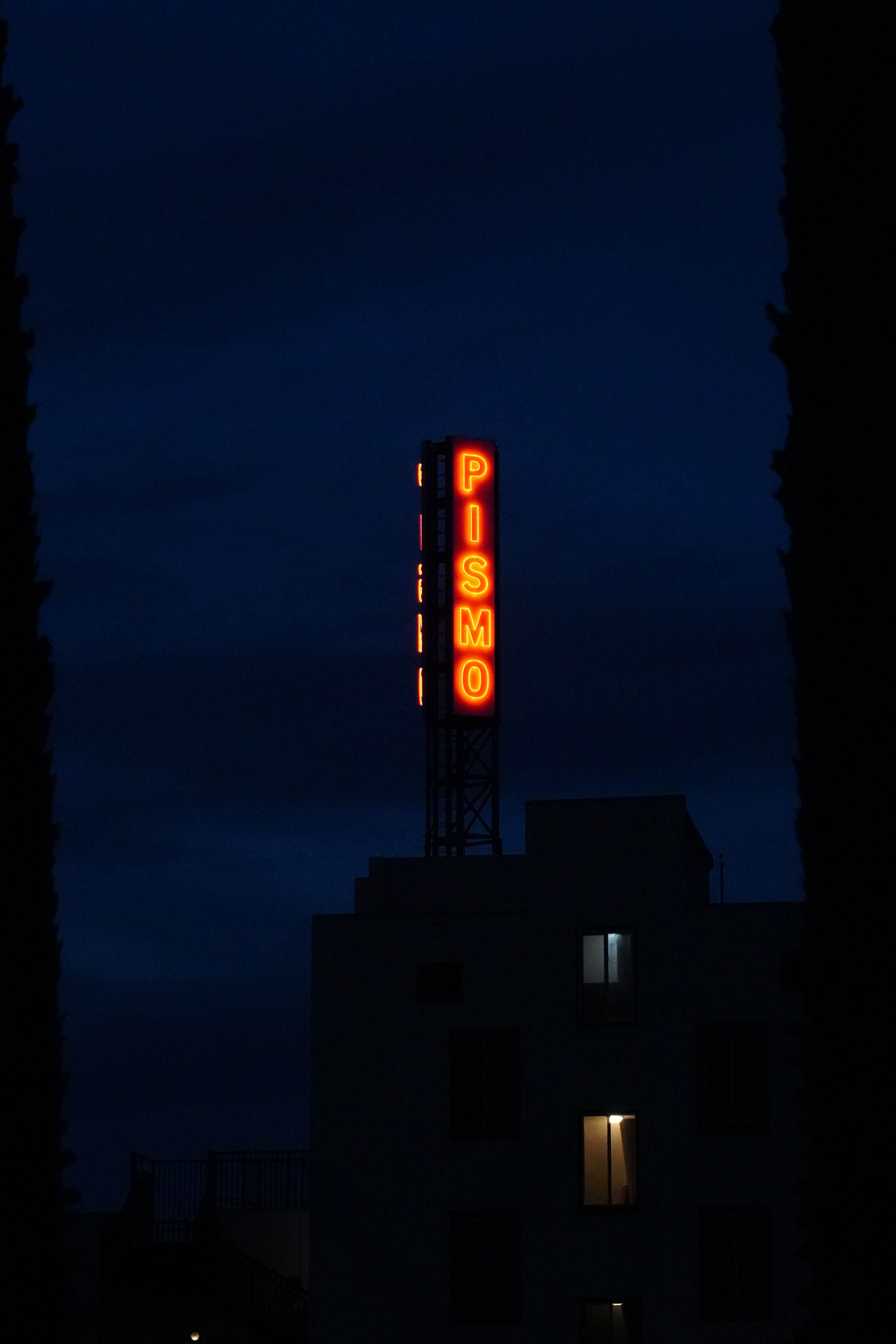 Dramatic night view of the Pismo Beach neon sign glowing against a dark sky.