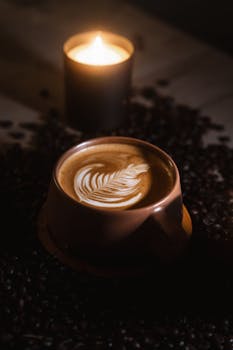 Warm and cozy coffee experience with latte art and candlelight setting, ideal for winter comforts.