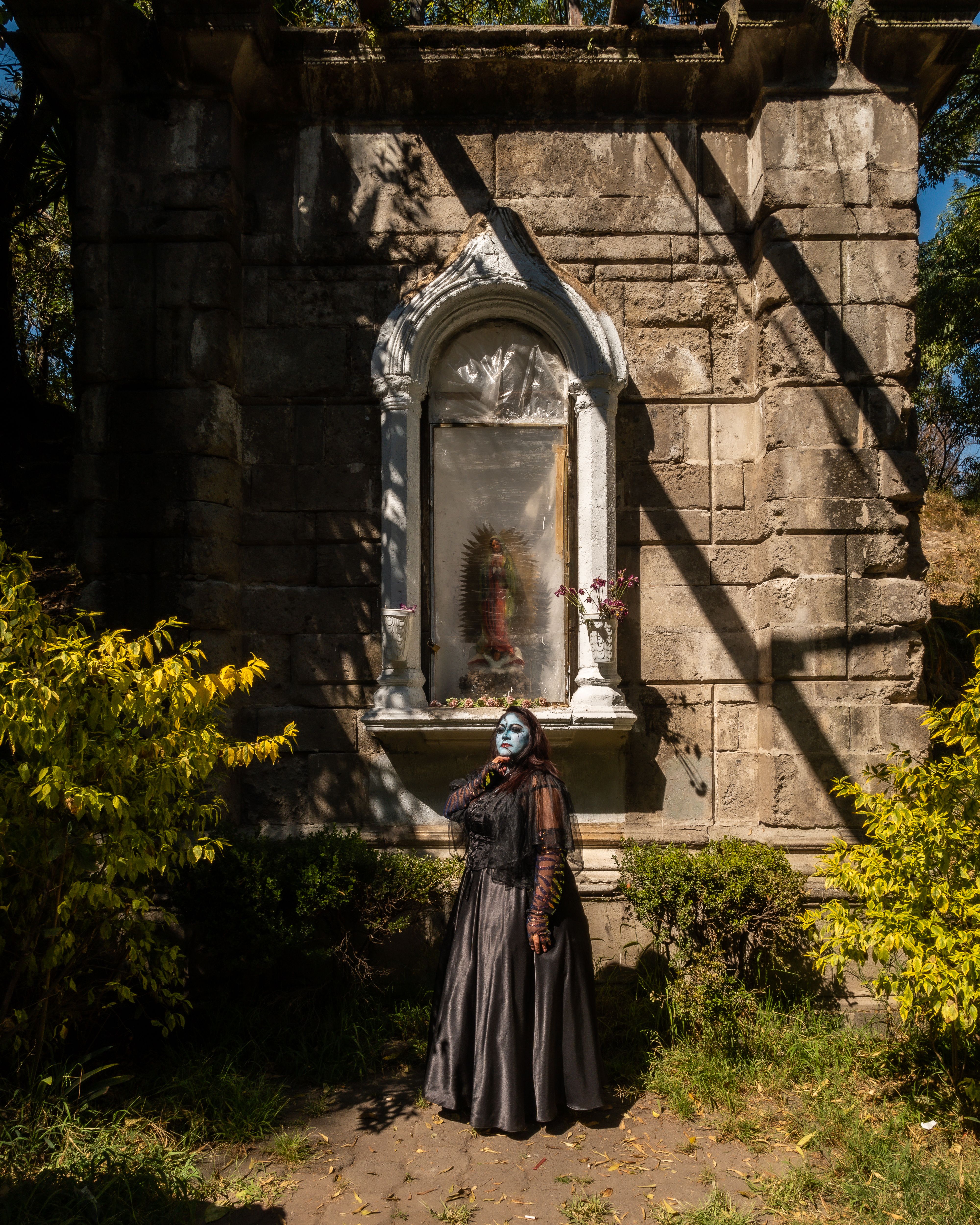 A surreal, gothic portrait in a Mexican cemetery with vibrant colors and dark ambiance.