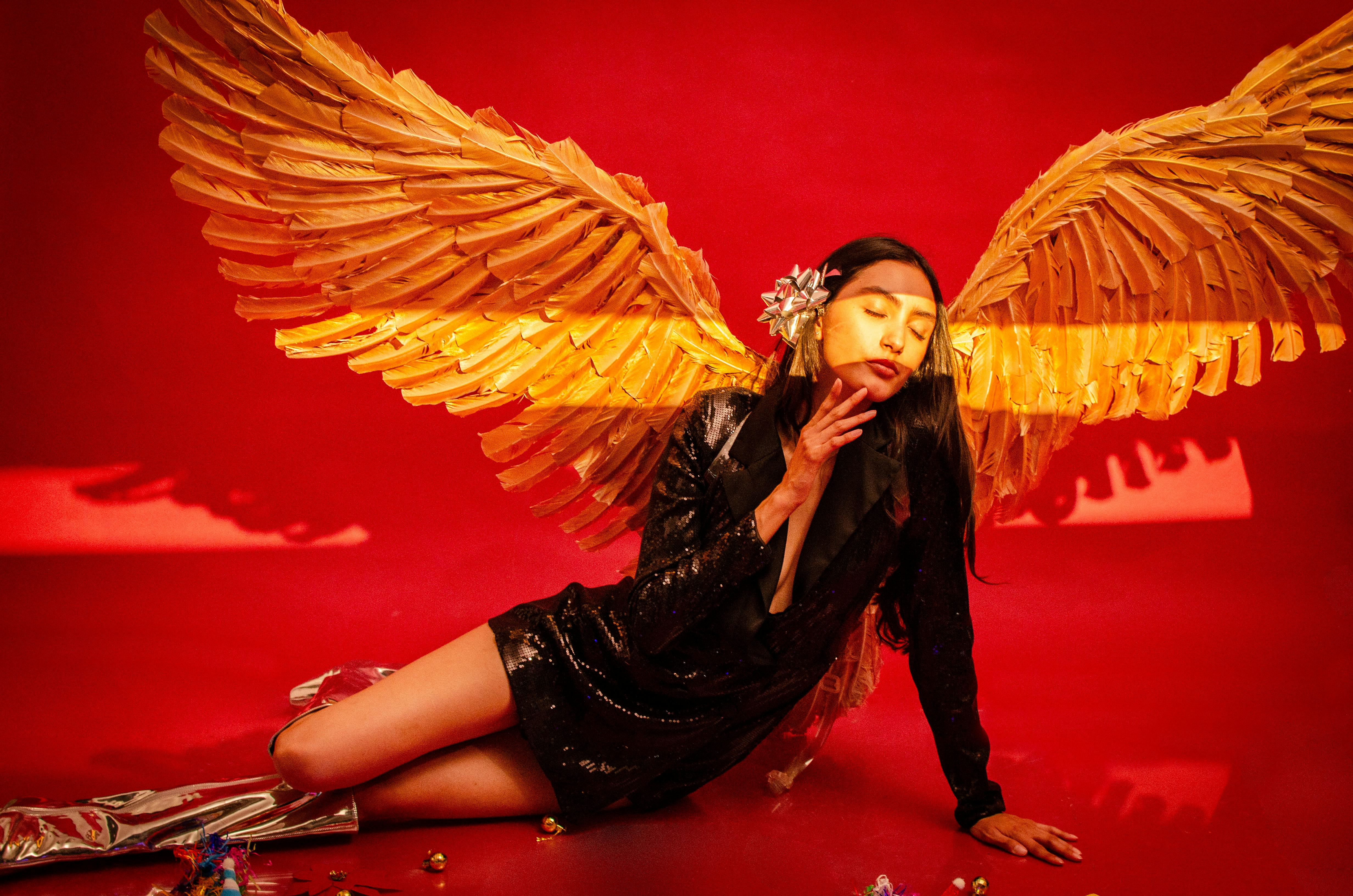 Zadarmo Elegantný módny portrét so zlatými krídlami a žiarivým červeným pozadím. Fotka z fotobanky