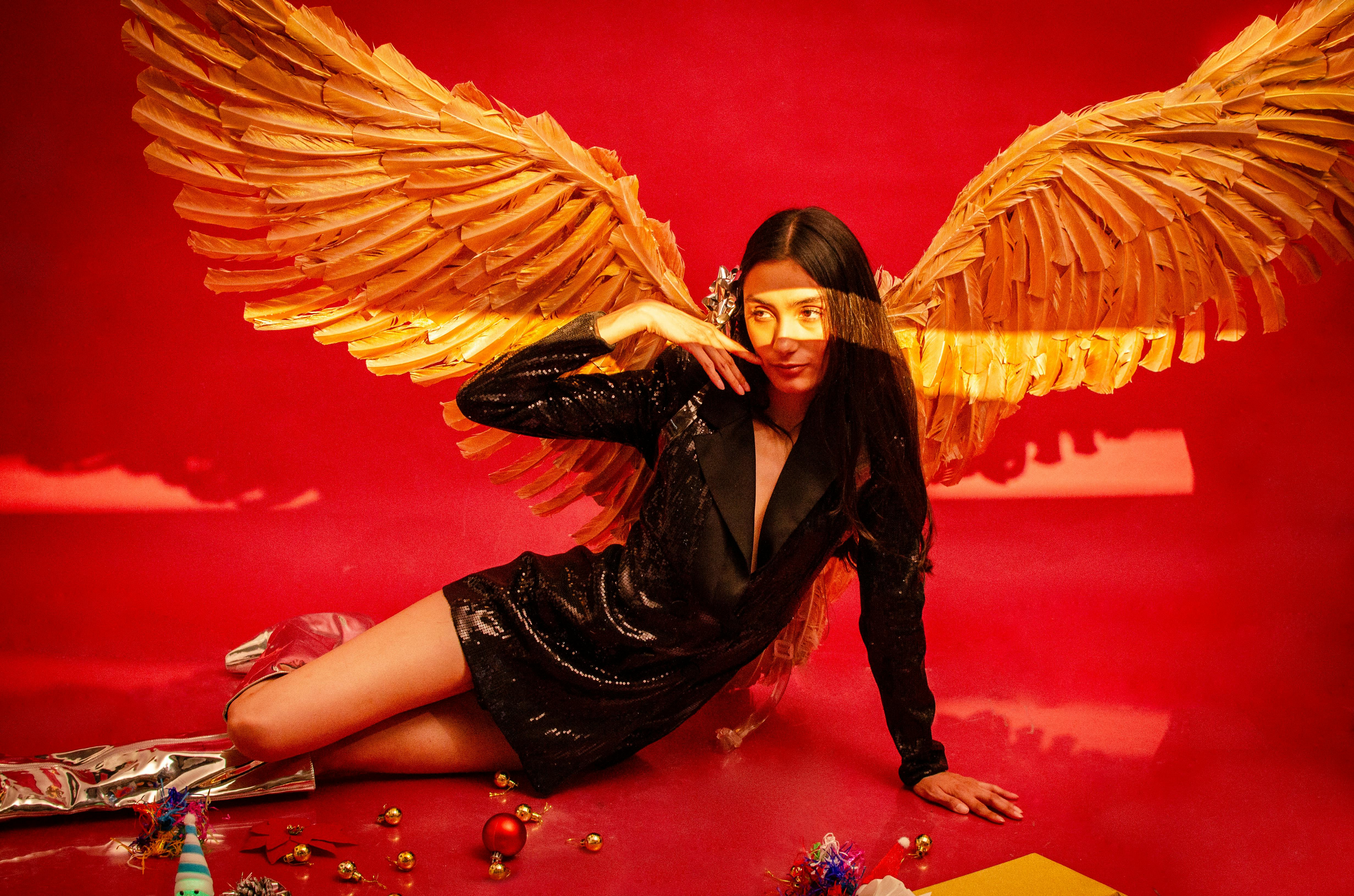 Gratis Seorang wanita bergaya dengan sayap emas dalam suasana Natal yang meriah. Foto Stok