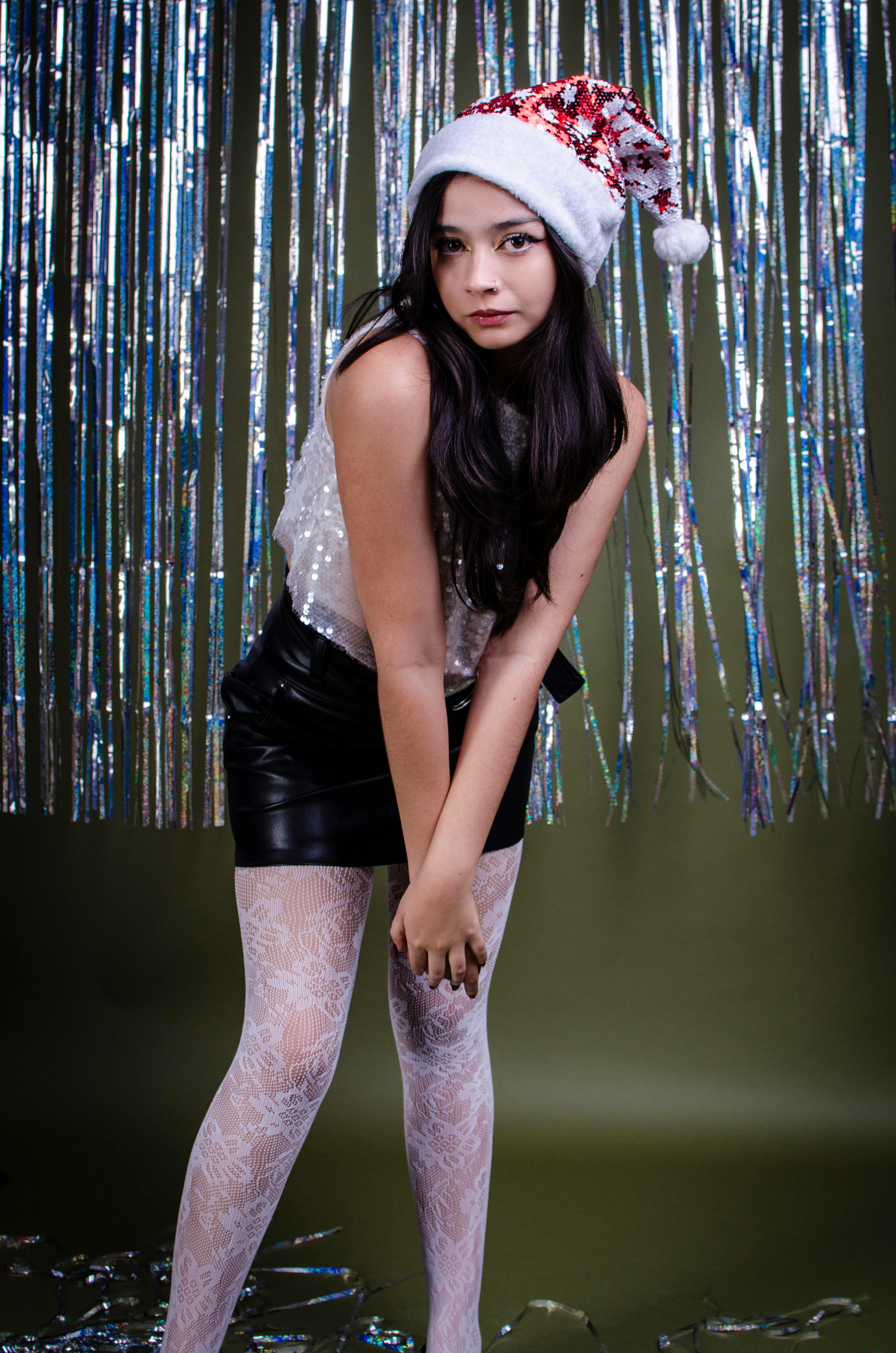 De franc Dona jove amb vestits festius amb barret de Pare Noel i teló de fons, celebrant la temporada de vacances. Foto d'estoc