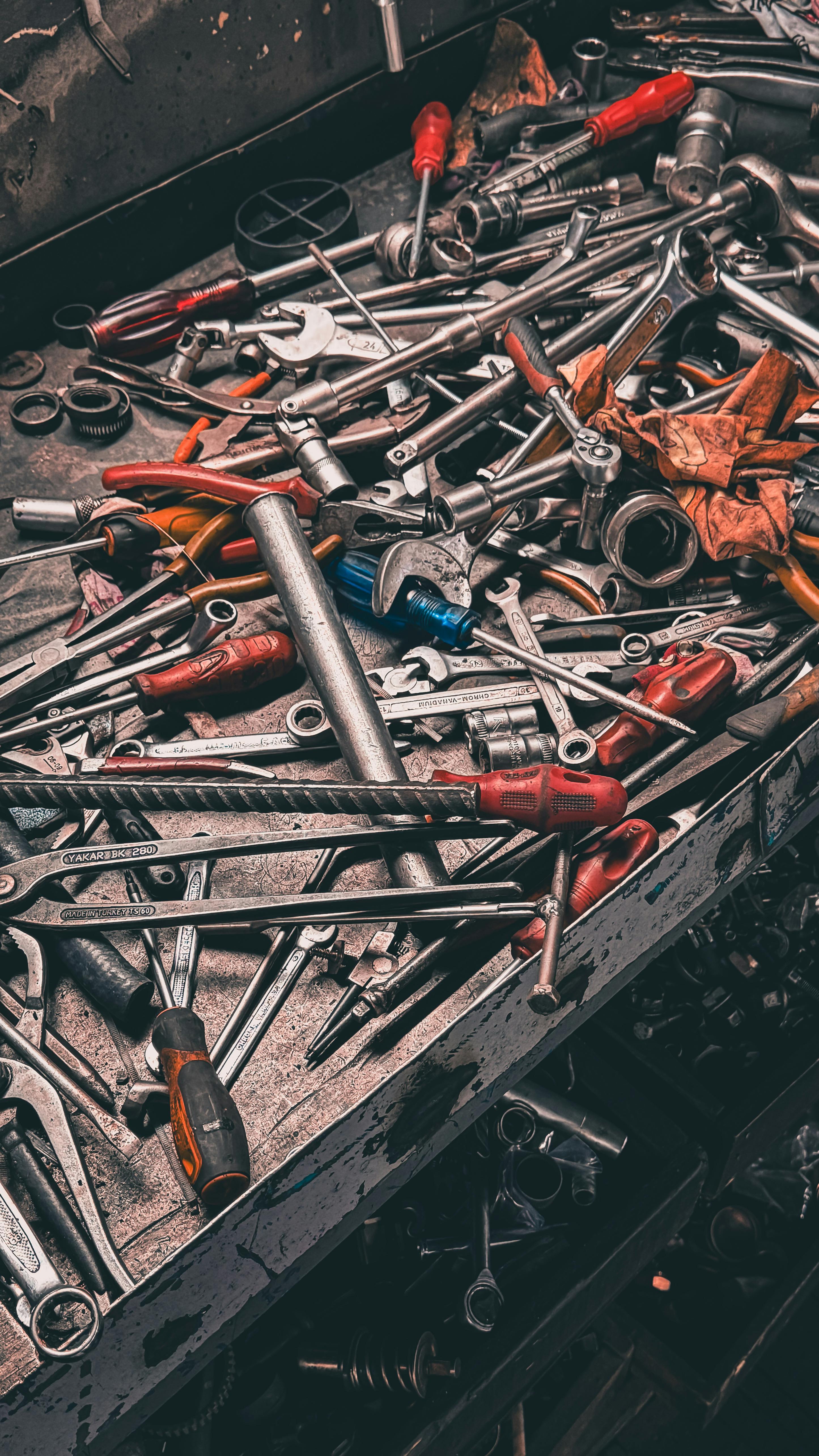 Assorted hand tools on a workbench in a garage workshop setting.
