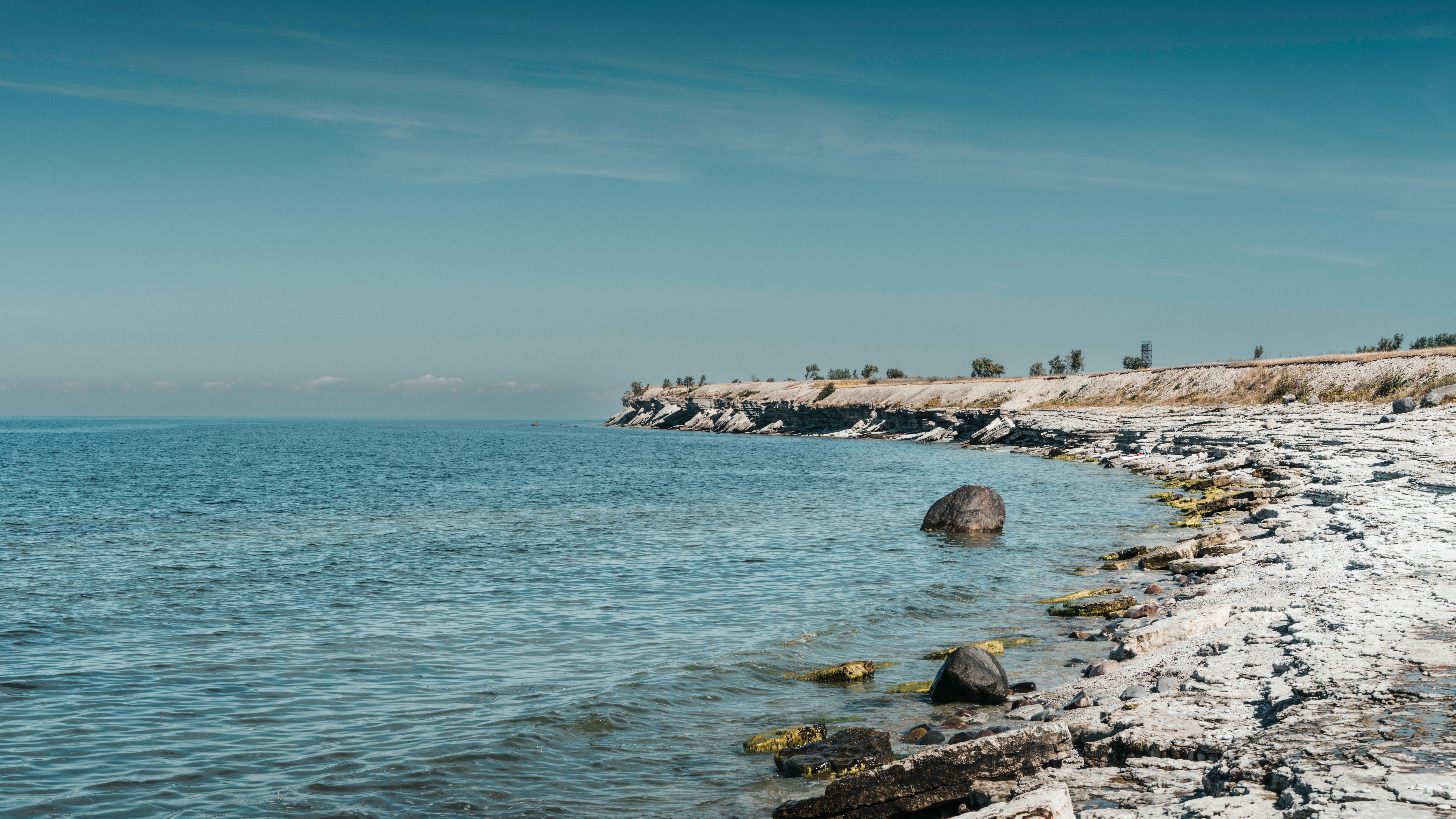 Scenic view of rocky coastal cliffs along tranquil blue waters under a clear sky. — Trójmiasto