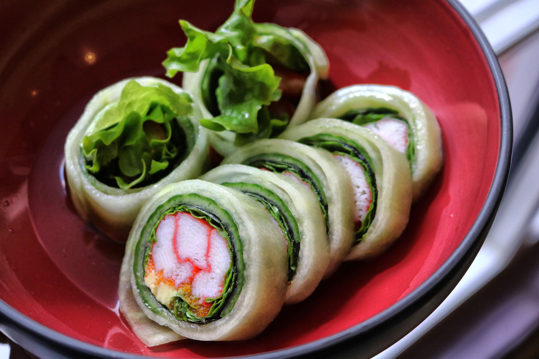 Fresh Spring Appetizers to Wow Your Guests Close-up of Japanese sushi rolls with vegetables served in a red bowl, highlighting freshness and vibrant colors.