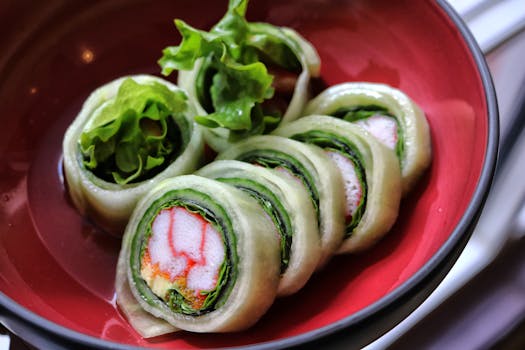 Close-up of Japanese sushi rolls with vegetables served in a red bowl, highlighting freshness and vibrant colors.