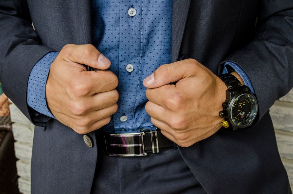 Close-up of a smartly dressed businessman adjusting his suit jacket, showcasing professional attire. Close-up of a smartly dressed businessman adjusting his suit jacket, showcasing professional attire.