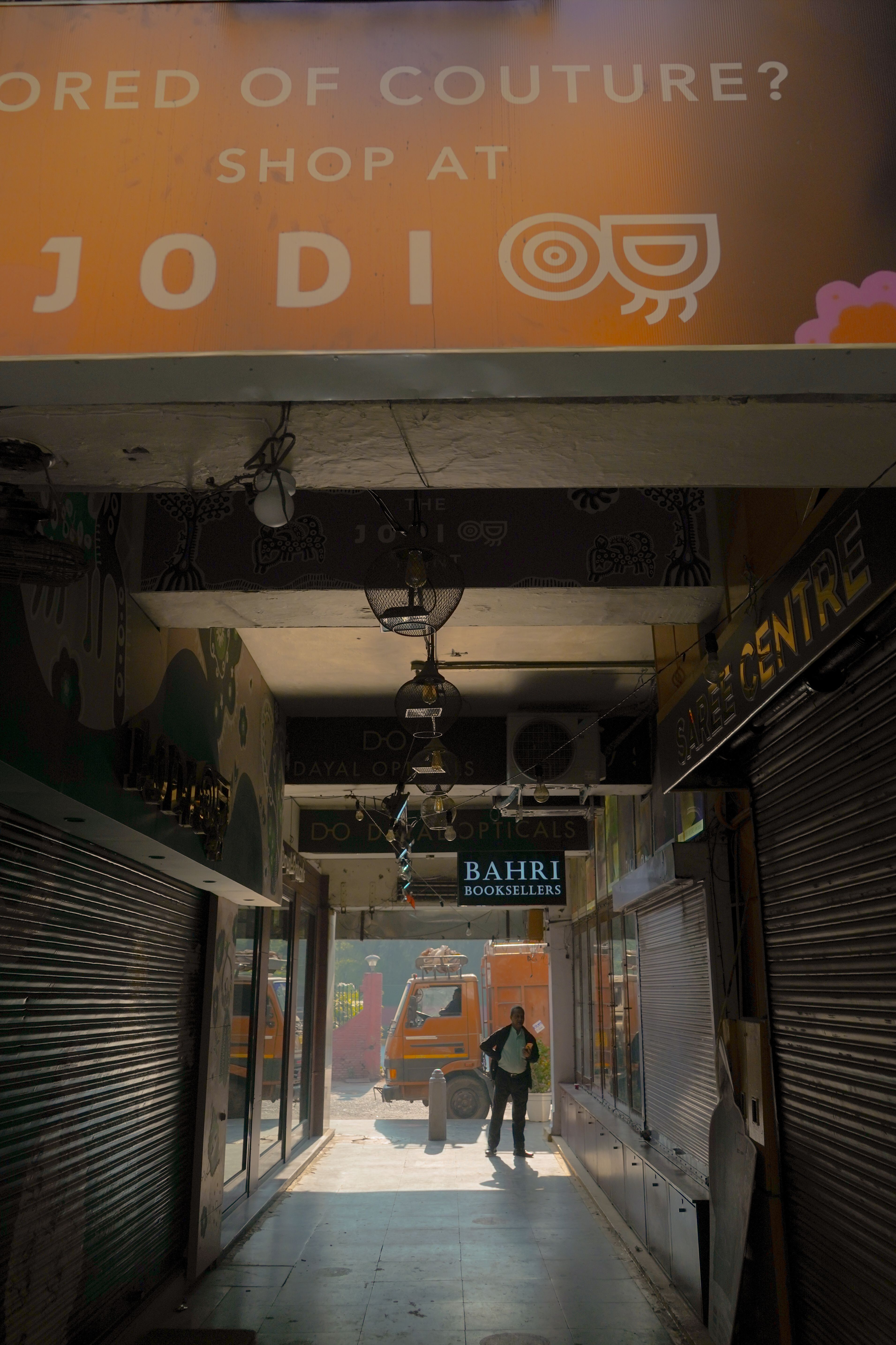 A quiet shopping alley with closed shops and a person under a warm sunlight glow.