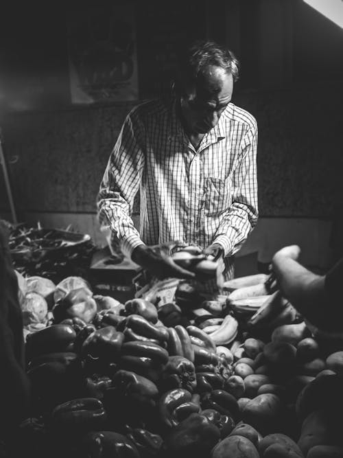 Grayscale Photo of Man Selecting Friuts