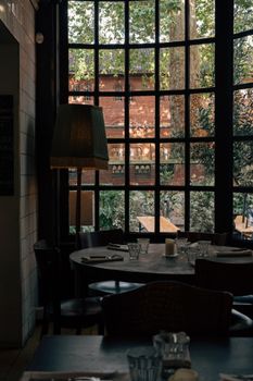 Charming cafe interior with large window showcasing a historic brick wall and garden.