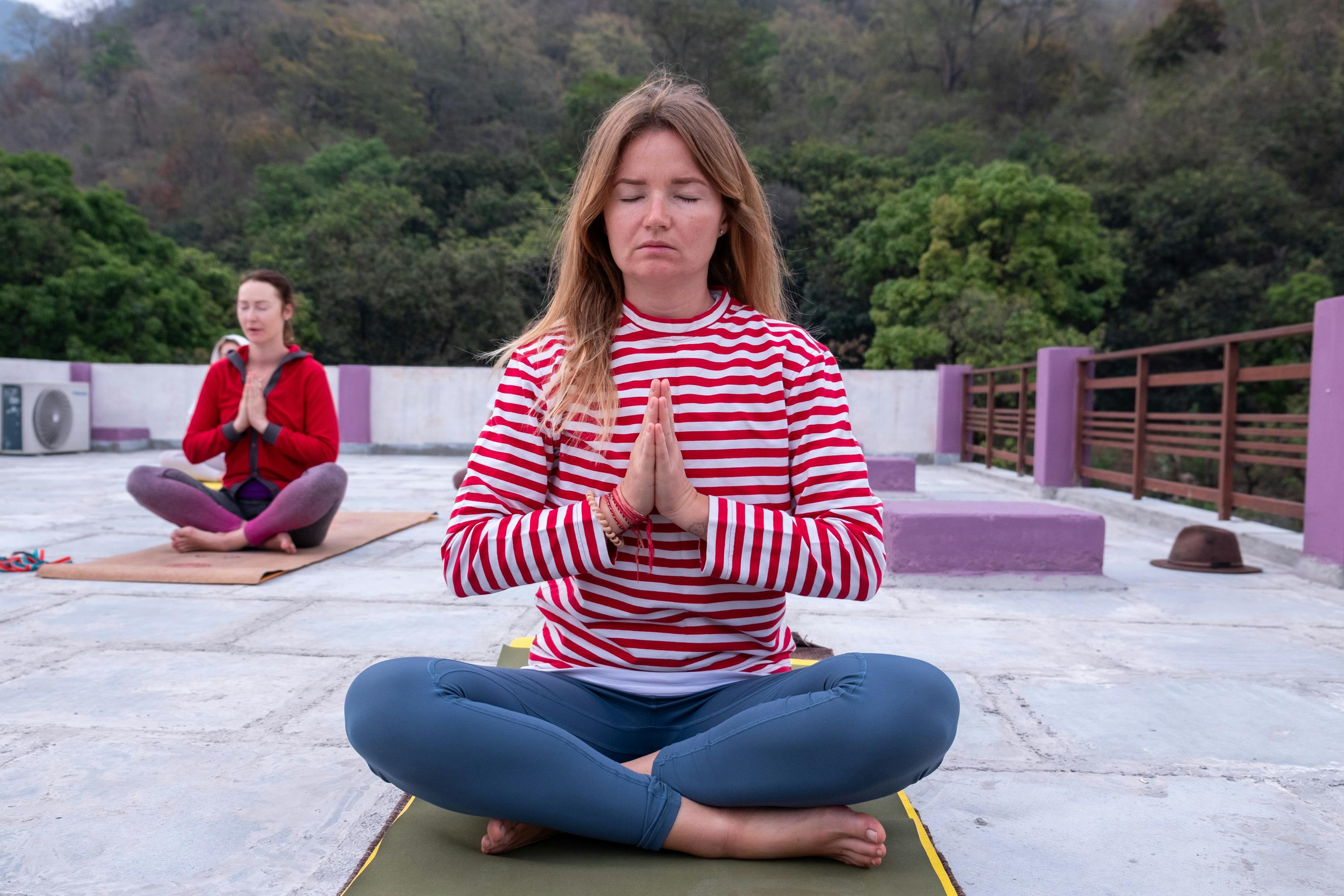Two women meditating outdoors in a peaceful yoga session.