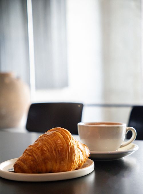 Free Inviting cafe scene featuring a warm croissant and steaming coffee in Kuantan, Malaysia. Stock Photo