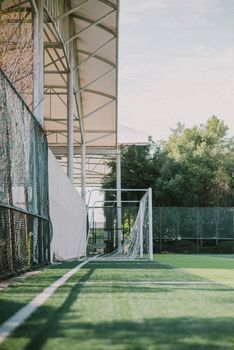 A serene outdoor soccer field with an empty goal net under a sunny sky, perfect for sports enthusiasts.