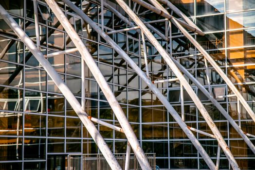 Elegant glass building facade with intersecting metal beams, showcasing modern architectural design.