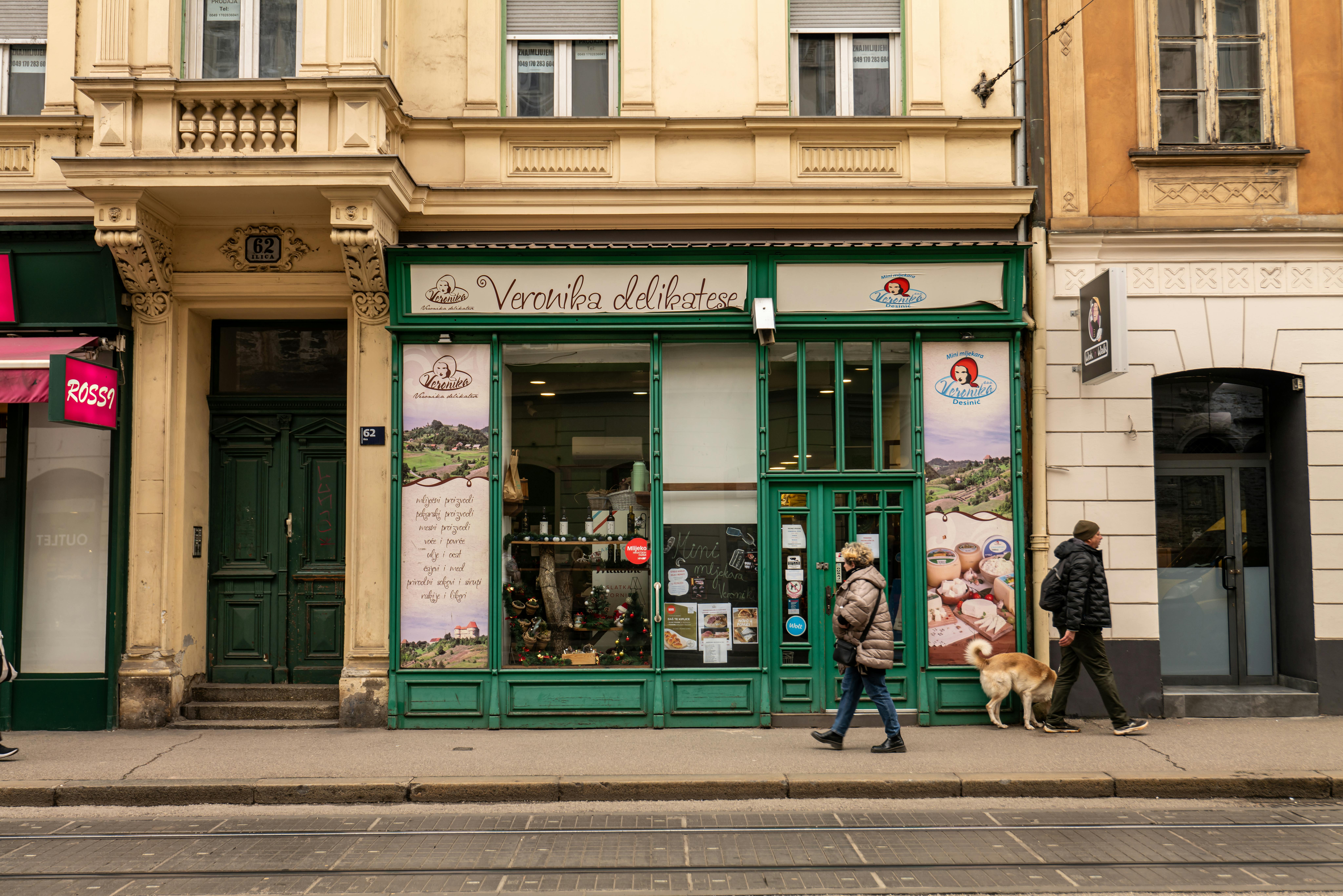 Street view of Veronika delicatessen shop with pedestrians passing in Zagreb, Croatia.