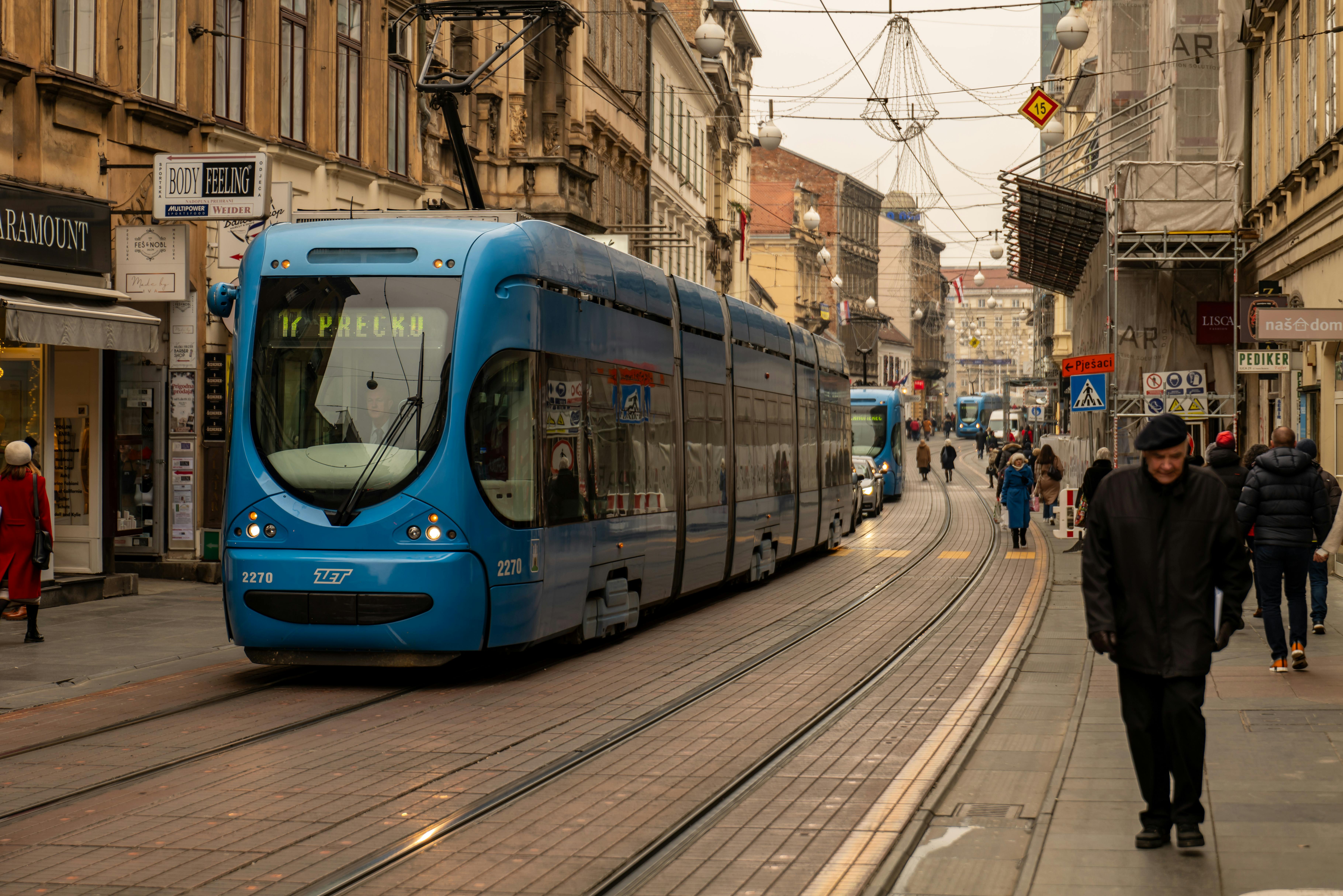 A blue tram travels through a bustling street in Zagreb, Croatia's capital city.