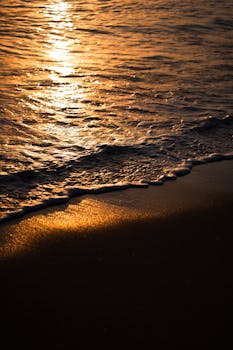 Beautiful sunset reflecting on Antalya beach waves and shore, showcasing vibrant colors.