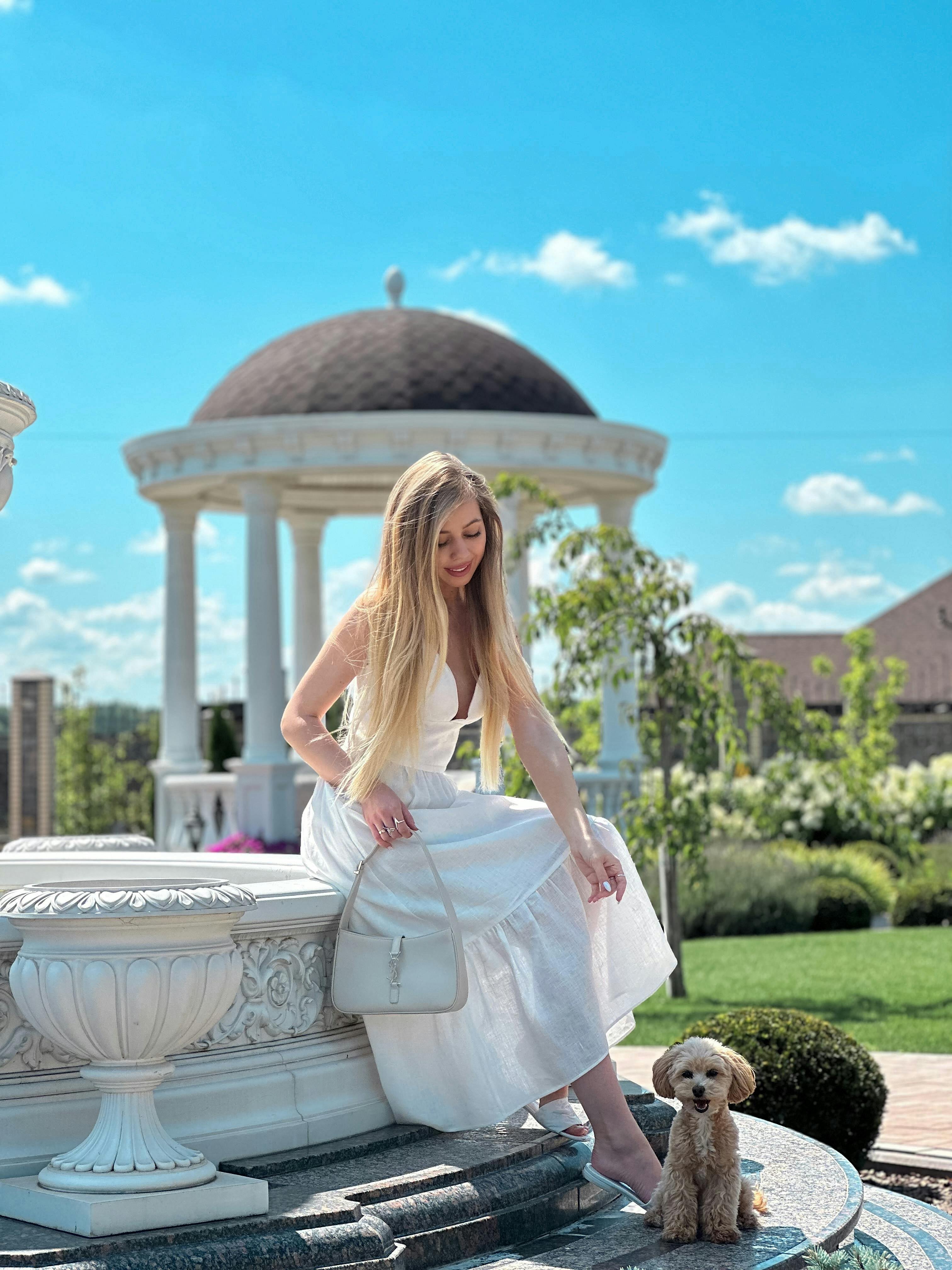 elegant woman with puppy in sunlit garden