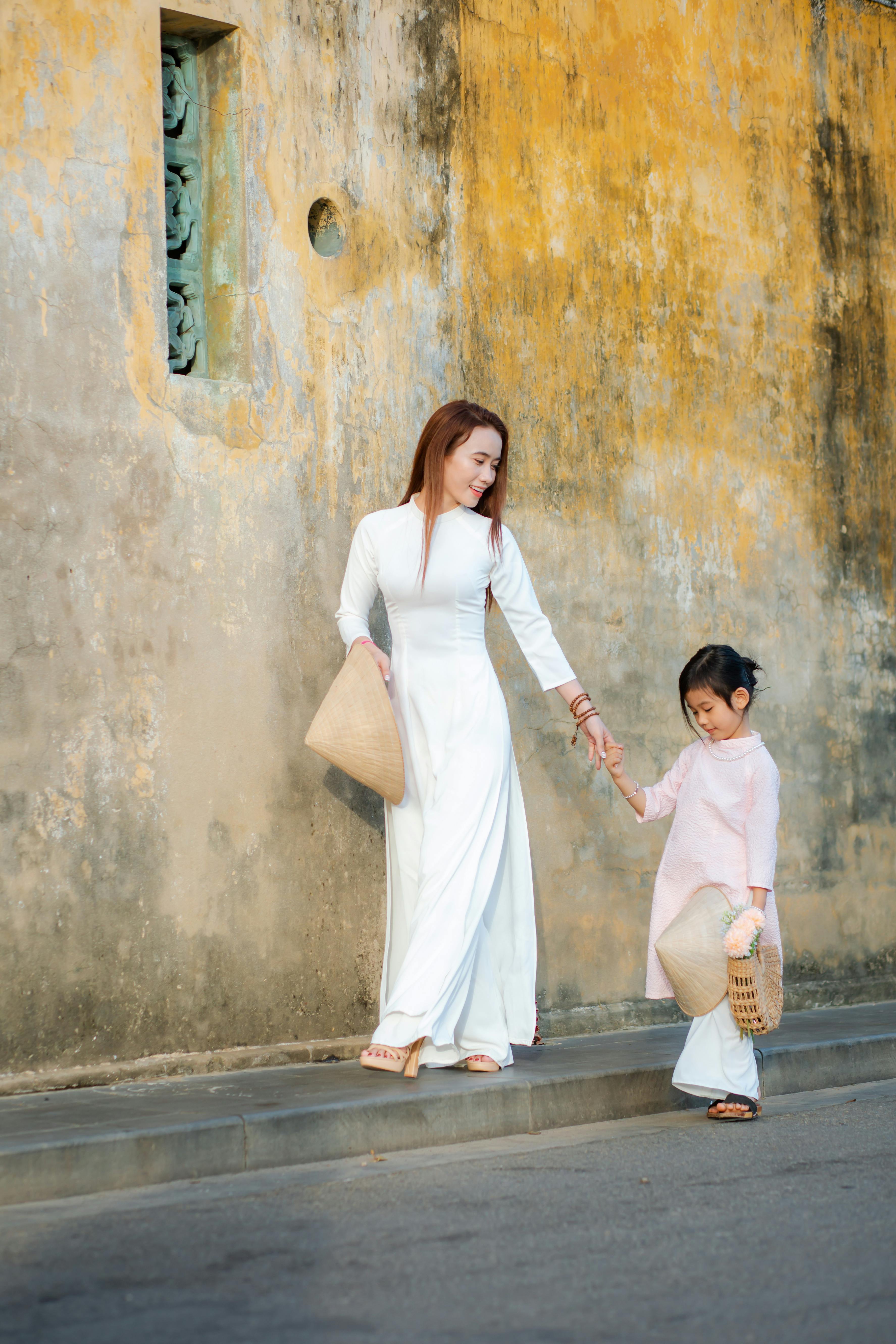 Mother and daughter in traditional Vietnamese ao dai walking in Hội An.