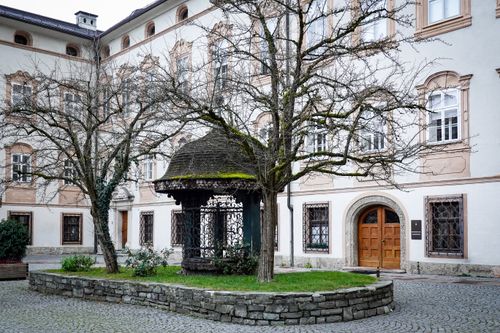 Free Charming European courtyard with historic architecture, leafless trees, and stone path. Stock Photo