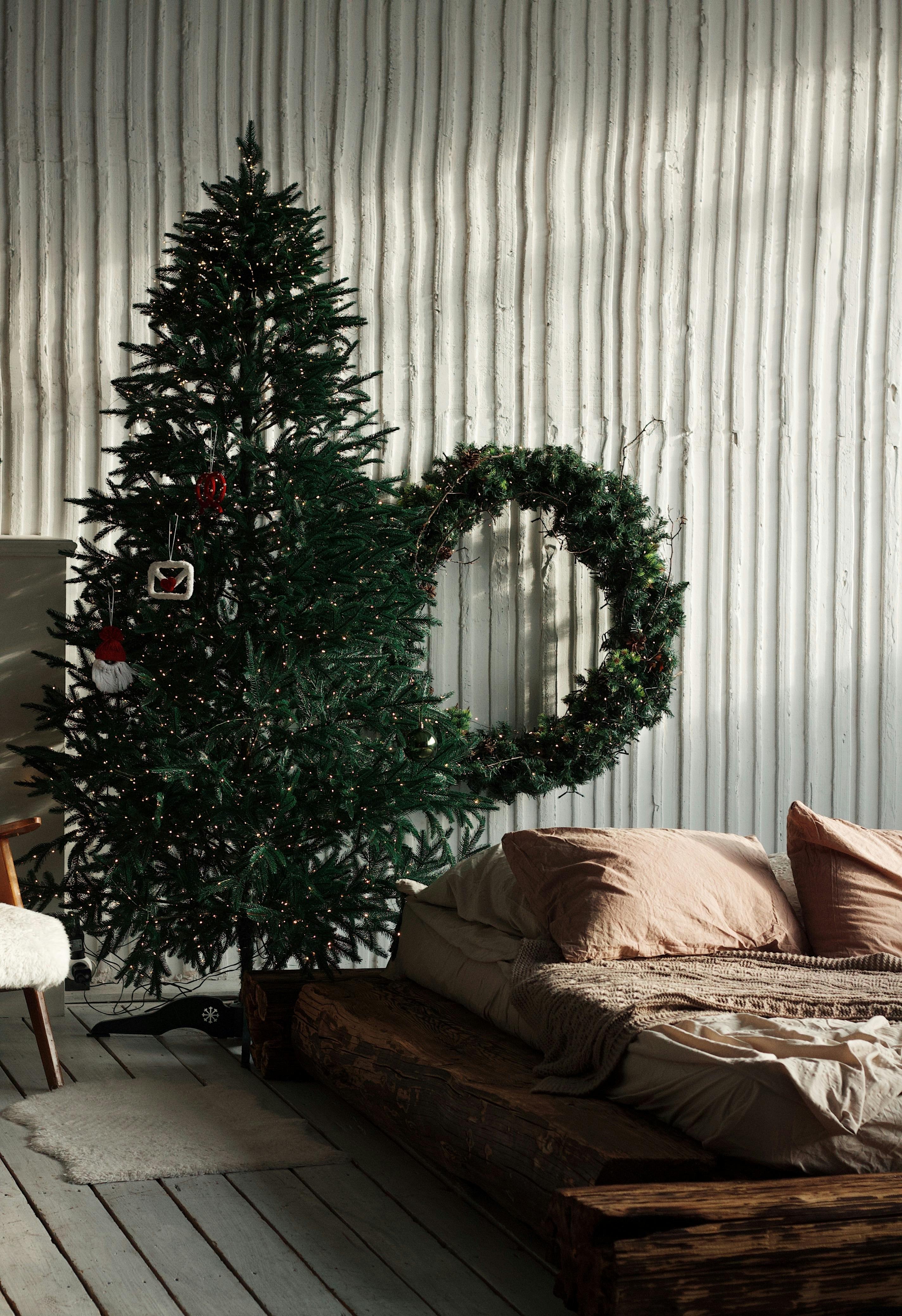Cozy bedroom decorated with a Christmas tree and wreath, creating a festive atmosphere.