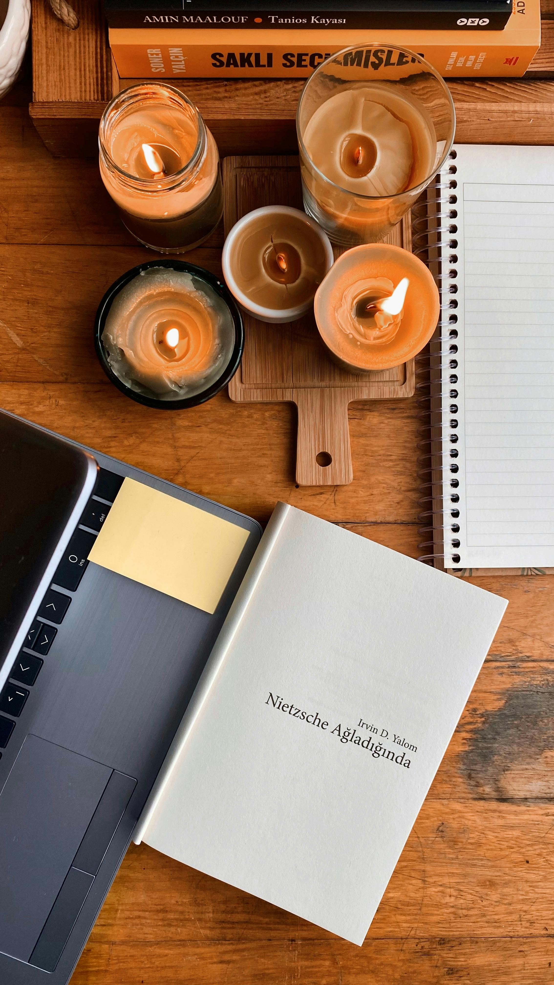 Inviting workspace featuring candles, a notebook, and a book for a warm, productive atmosphere.