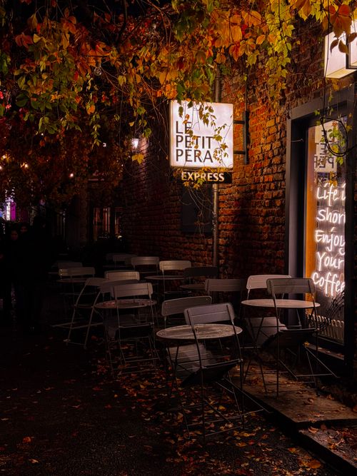 Free Charming cafe exterior at night adorned with autumn leaves, inviting for evening coffee. Stock Photo