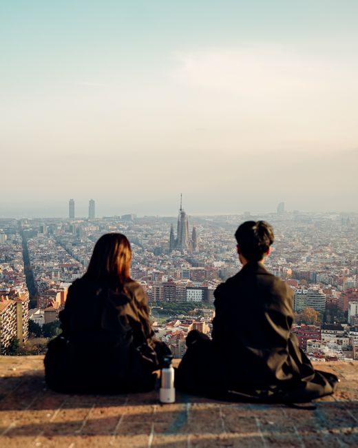 A couple enjoying a panoramic view of Barcelona, Spain with the Sagrada Familia in the distance.