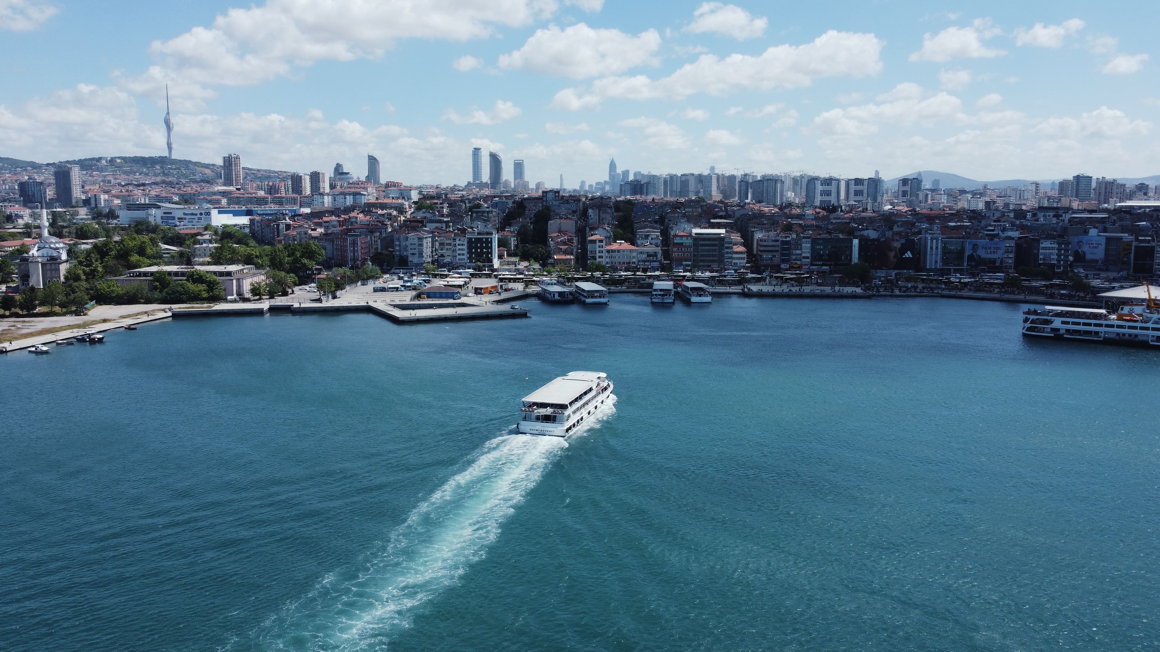 Aerial view of a ferry departing a dock in Kadikoy, Istanbul, with the skyline in the background.