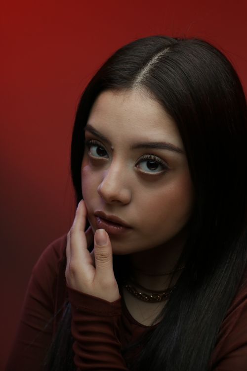 Free Close-up portrait of a young woman with long hair, dramatic red background. Stock Photo
