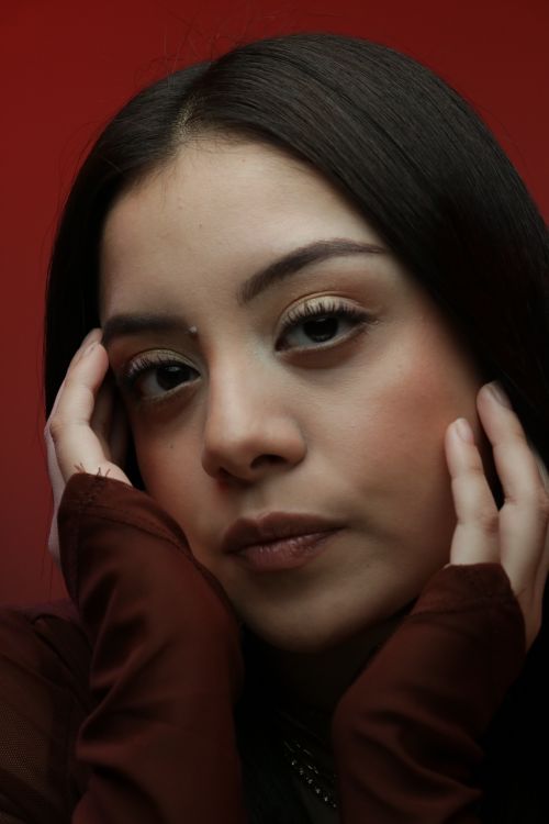 Free Portrait of a young woman with thoughtful expression against red background. Stock Photo