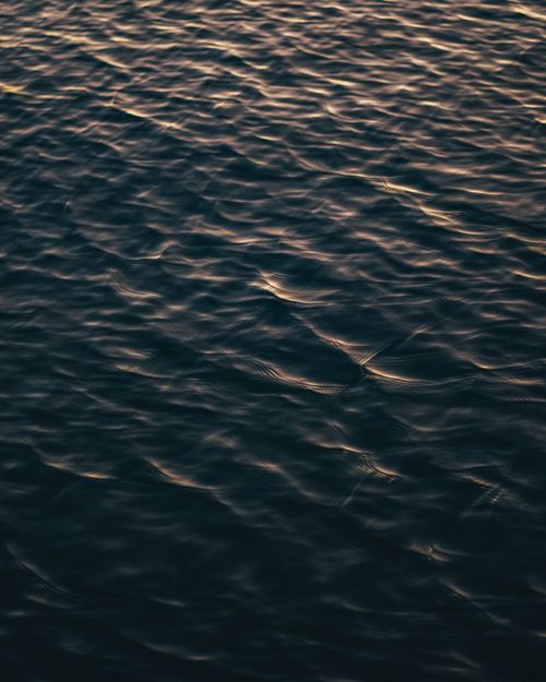 Free Serene ocean waters reflecting the warm glow of sunset light. Stock Photo