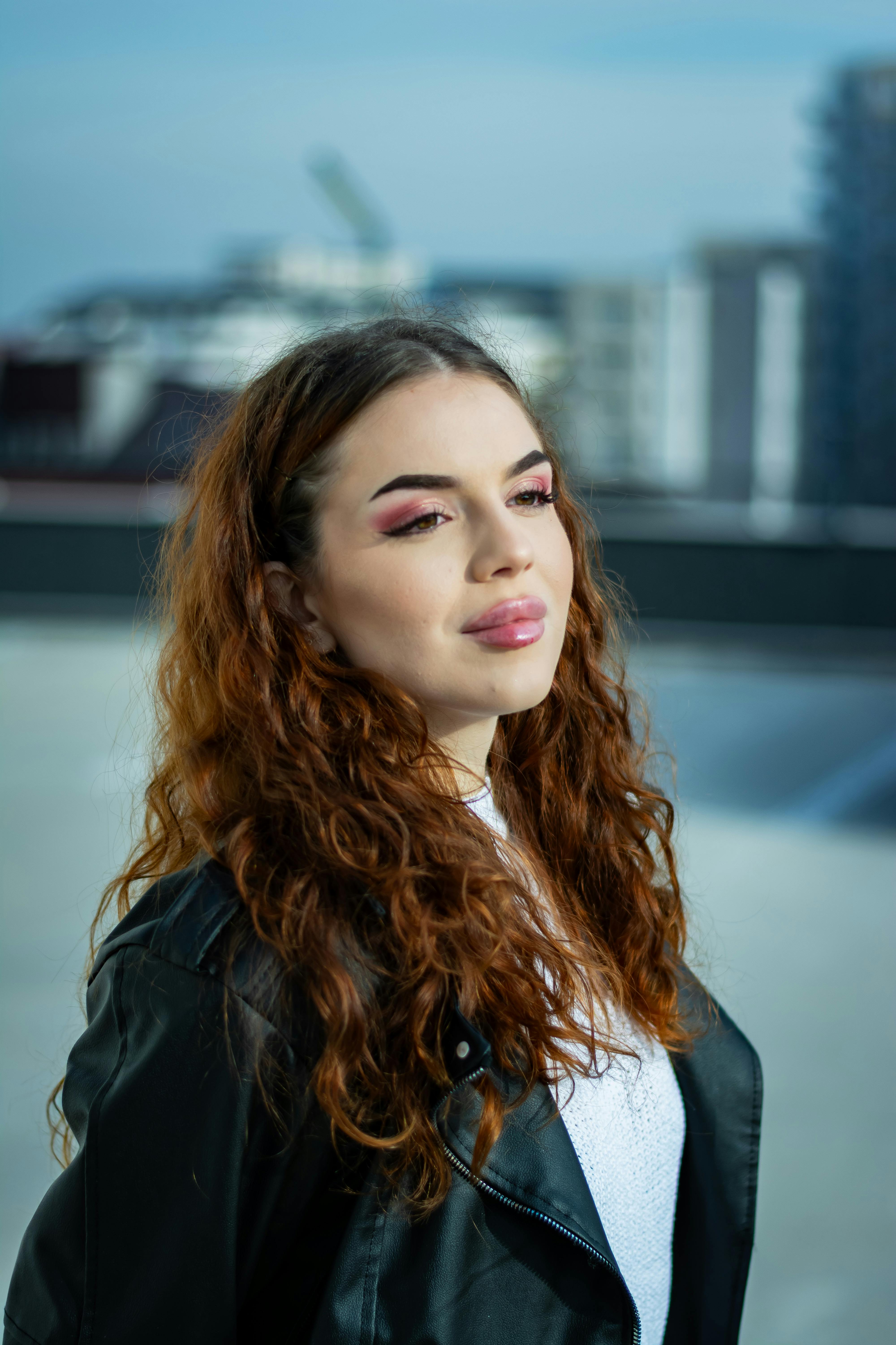 A young woman with curly hair in an urban environment, highlighting modern fashion.