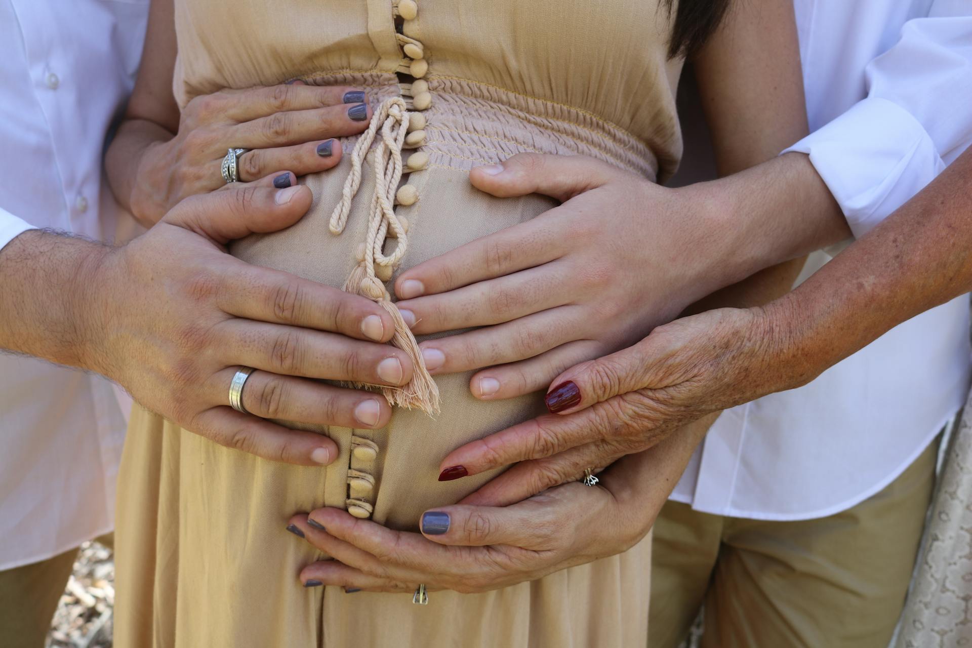 Close-up of family hands touching a pregnant belly, symbolizing love and support during pregnancy.