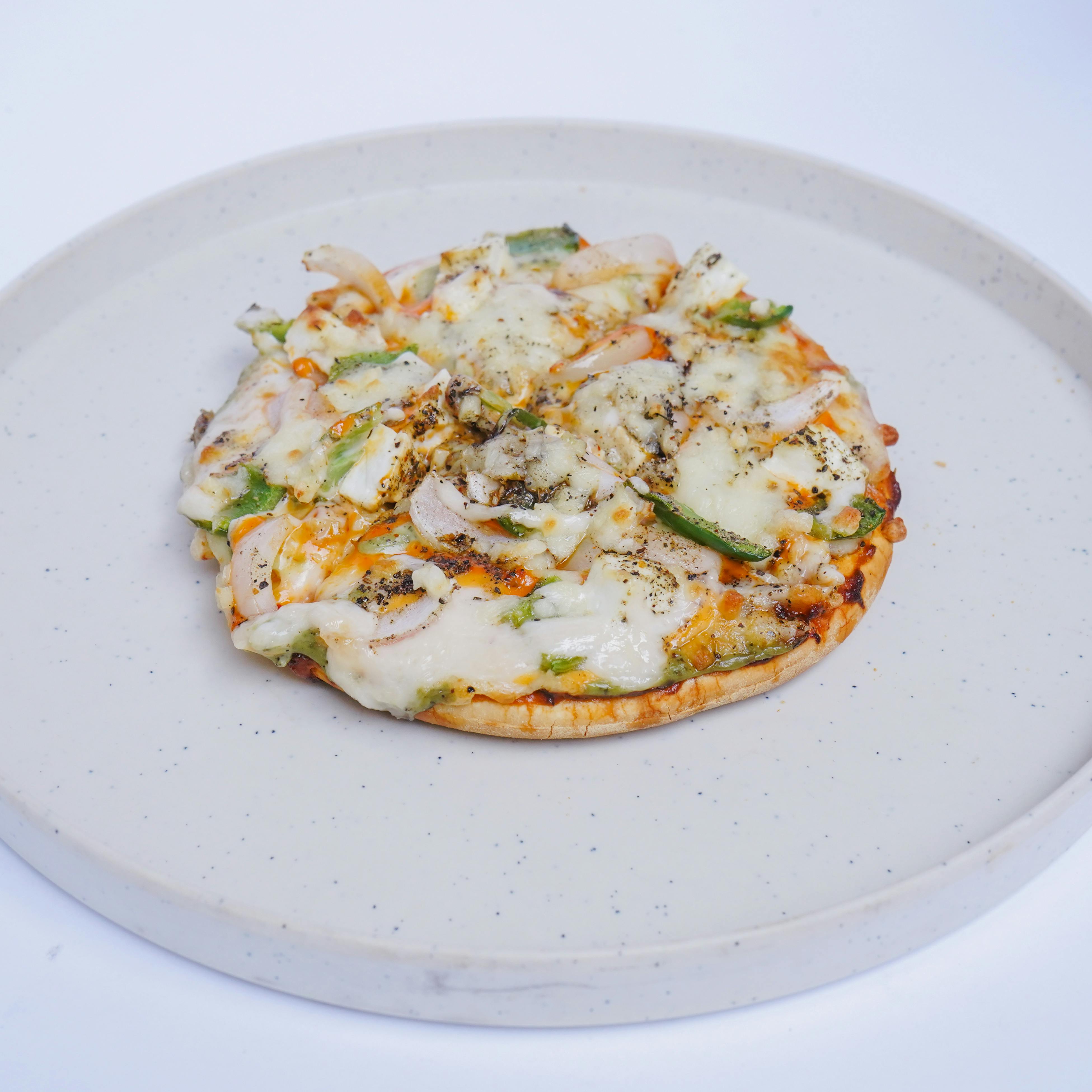 Appetizing cheese and vegetable pizza on ceramic plate, perfect for food lovers.