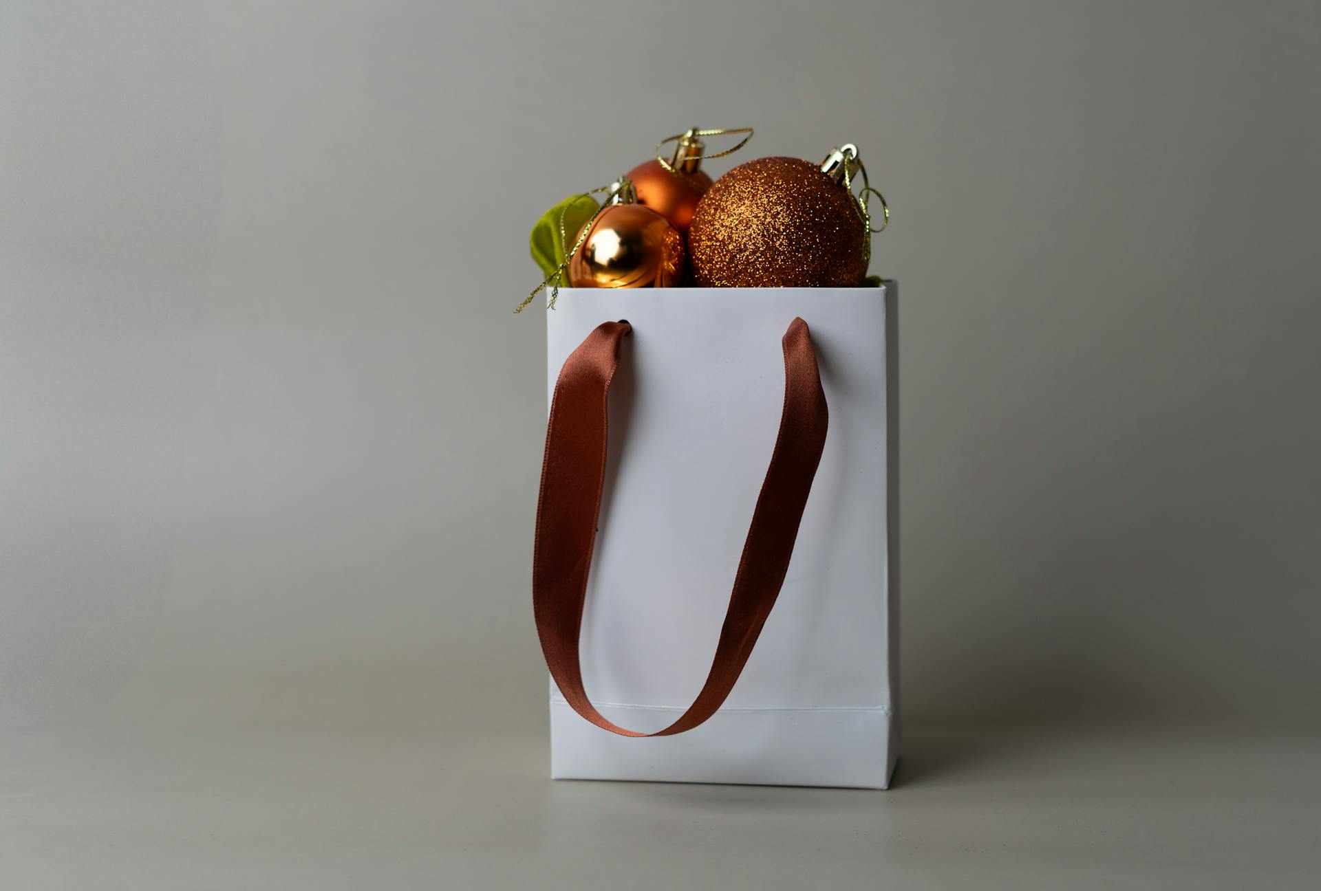 A white gift bag filled with sparkling Christmas ornaments showcasing elegant holiday decor.