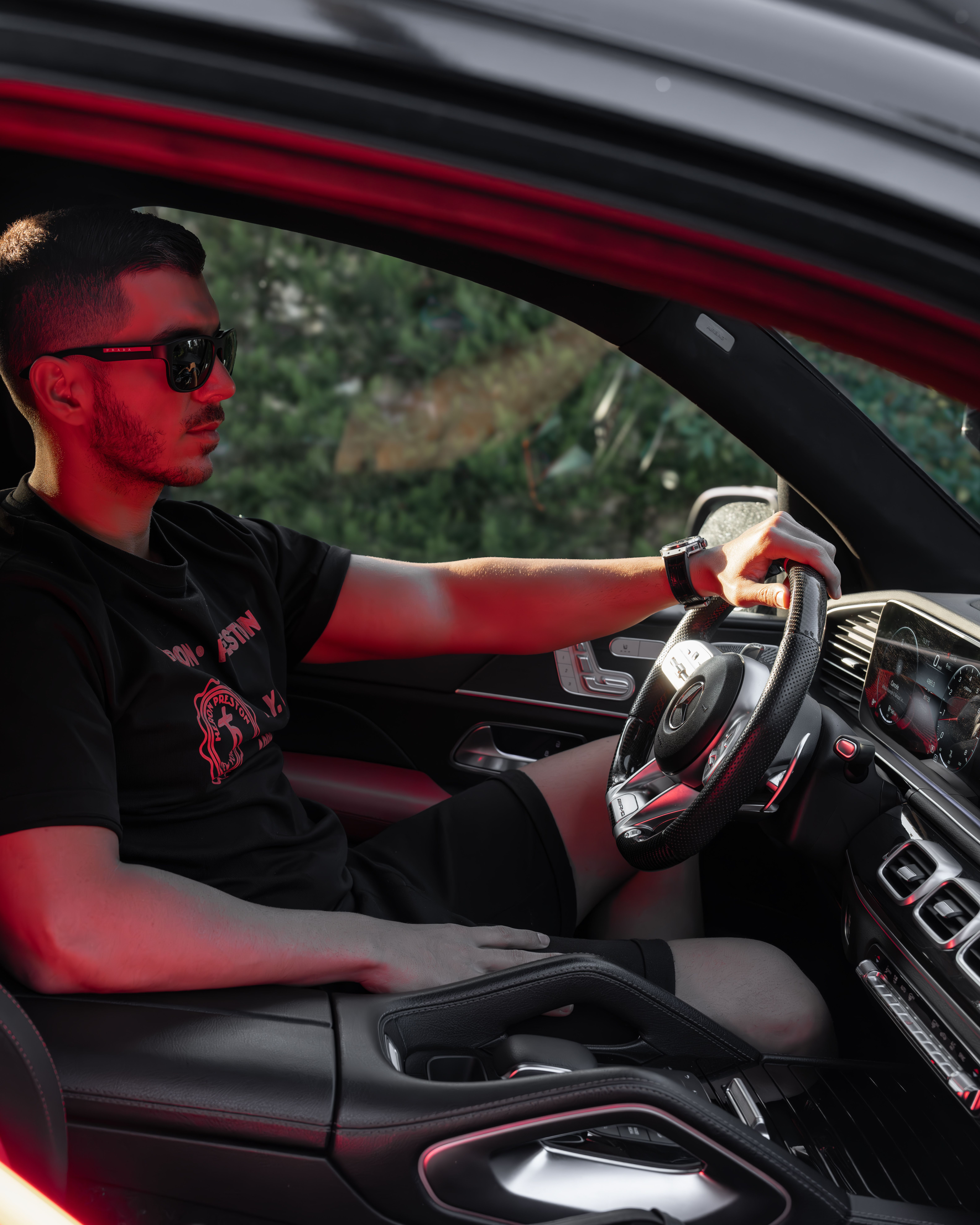 Young man in sunglasses driving a luxury car, showcasing modern automotive style.