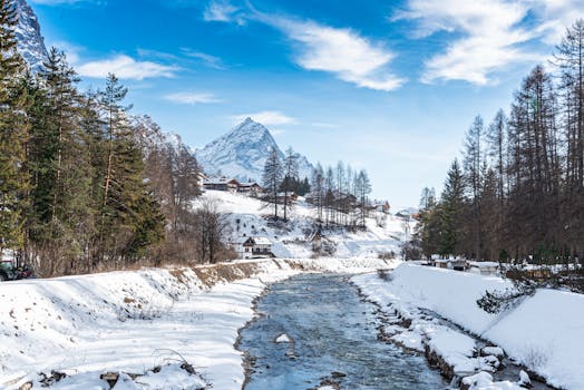 Serene winter scene of a snowy landscape and stream in Cortina d'Ampezzo, Italy.