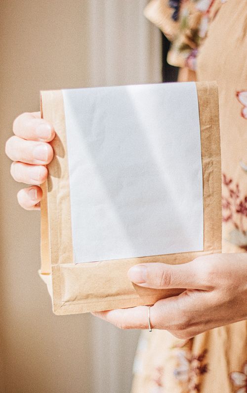 Free Minimalist brown coffee bag held with a blank label, perfect for branding and packaging concepts. Stock Photo