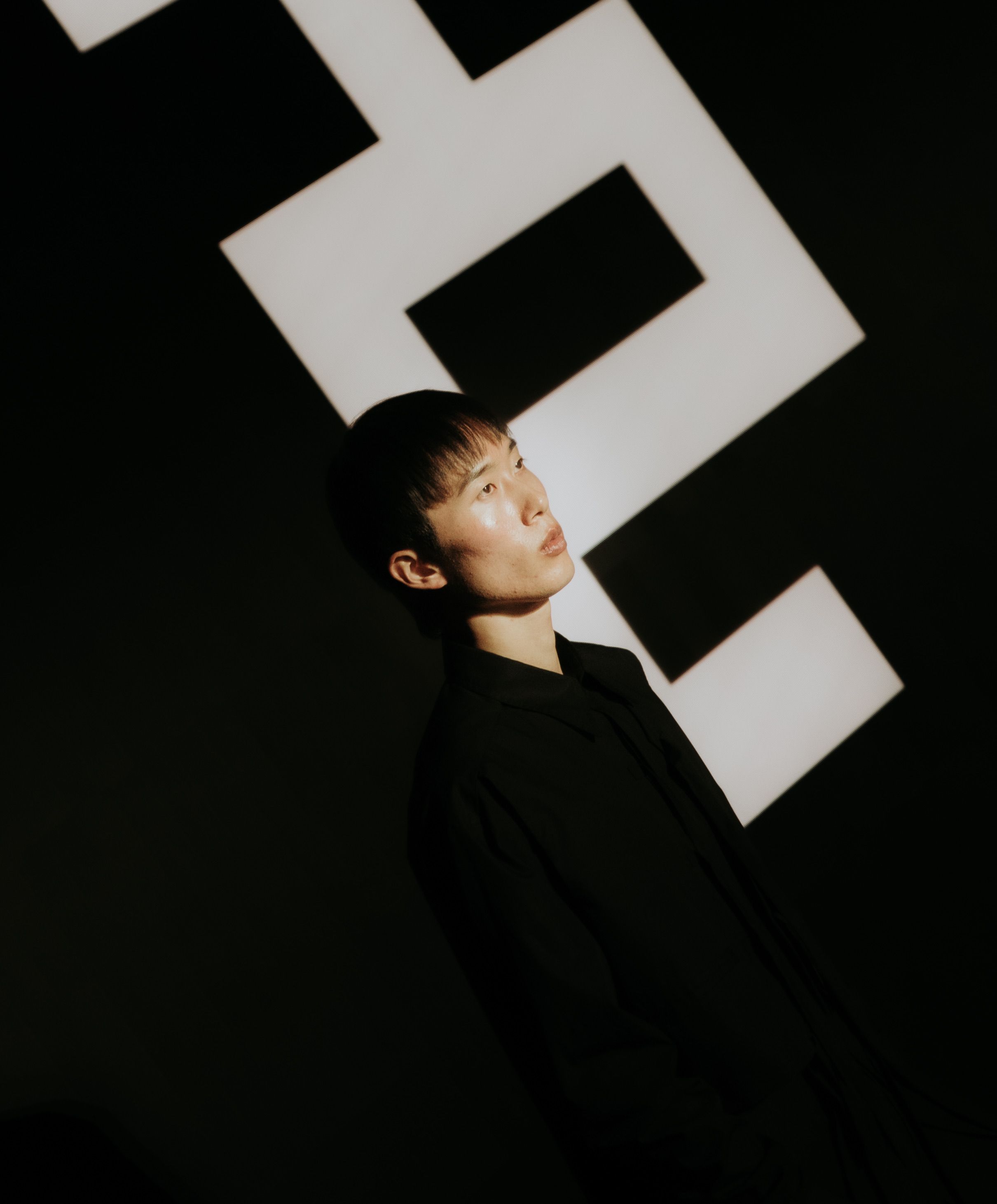 Artistic portrait of a young adult in a stylish pose against a bold geometric backdrop, creating a modern fashion statement.