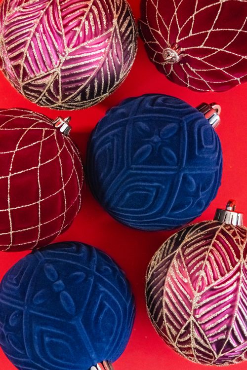 Free Colorful Christmas ornaments with intricate designs on a red surface, perfect for holiday decor. Stock Photo