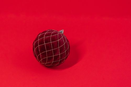 Free A velvet red Christmas ornament with a grid pattern on a vivid red backdrop, perfect for festive designs. Stock Photo