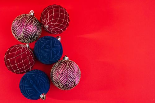 Free Festive Christmas baubles arranged on a vibrant red background, ideal for holiday themes. Stock Photo