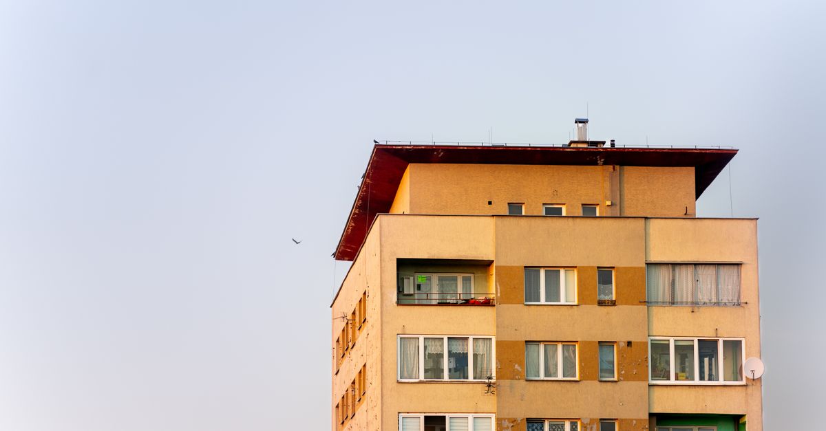 A modern apartment building with balconies against a clear sky, showcasing urban living.