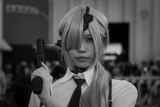A striking black and white portrait of a cosplay character holding a gun prop, exuding intensity.