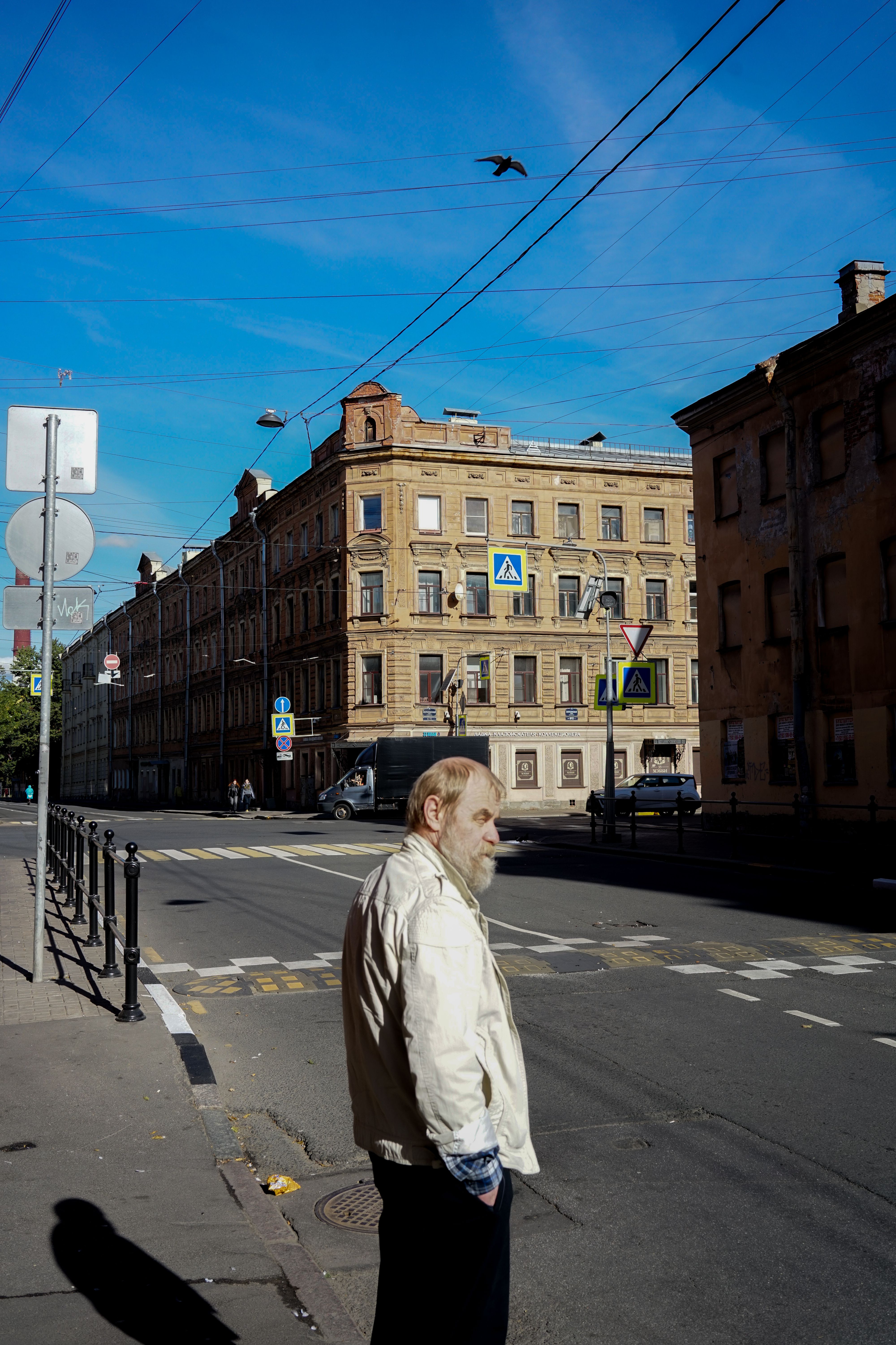 A man stands on a quiet sunny street in front of historical buildings.