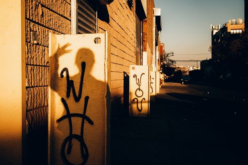 Free Artistic shadow cast on a graffiti-covered urban wall with warm sunset lighting. Stock Photo