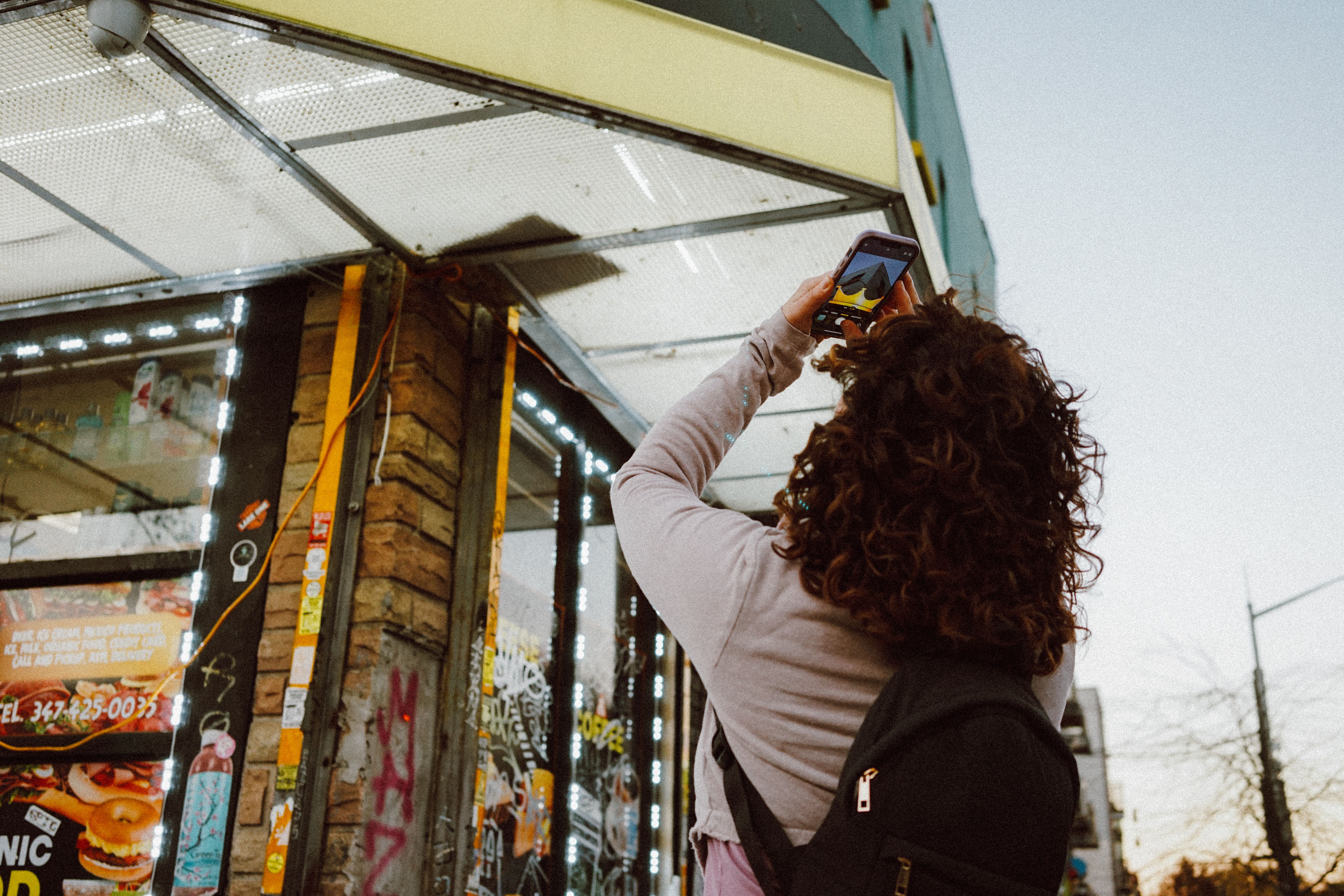 Une personne photographie l'art de rue urbain à l'aide d'un smartphone, capturant l'atmosphère vibrante de la ville.