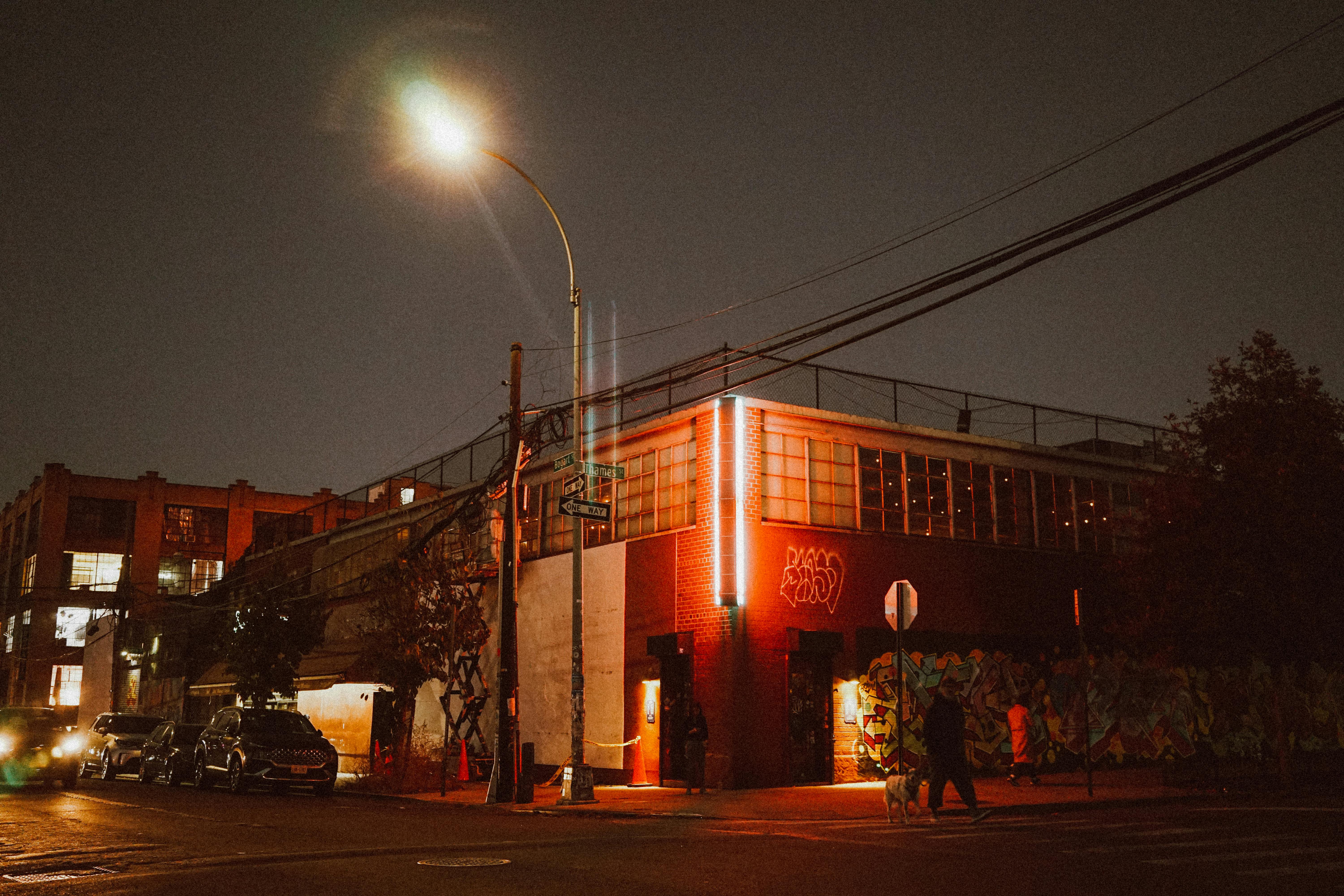 Free Vibrant night street scene of a city corner with illuminated graffiti and streetlights. Stock Photo