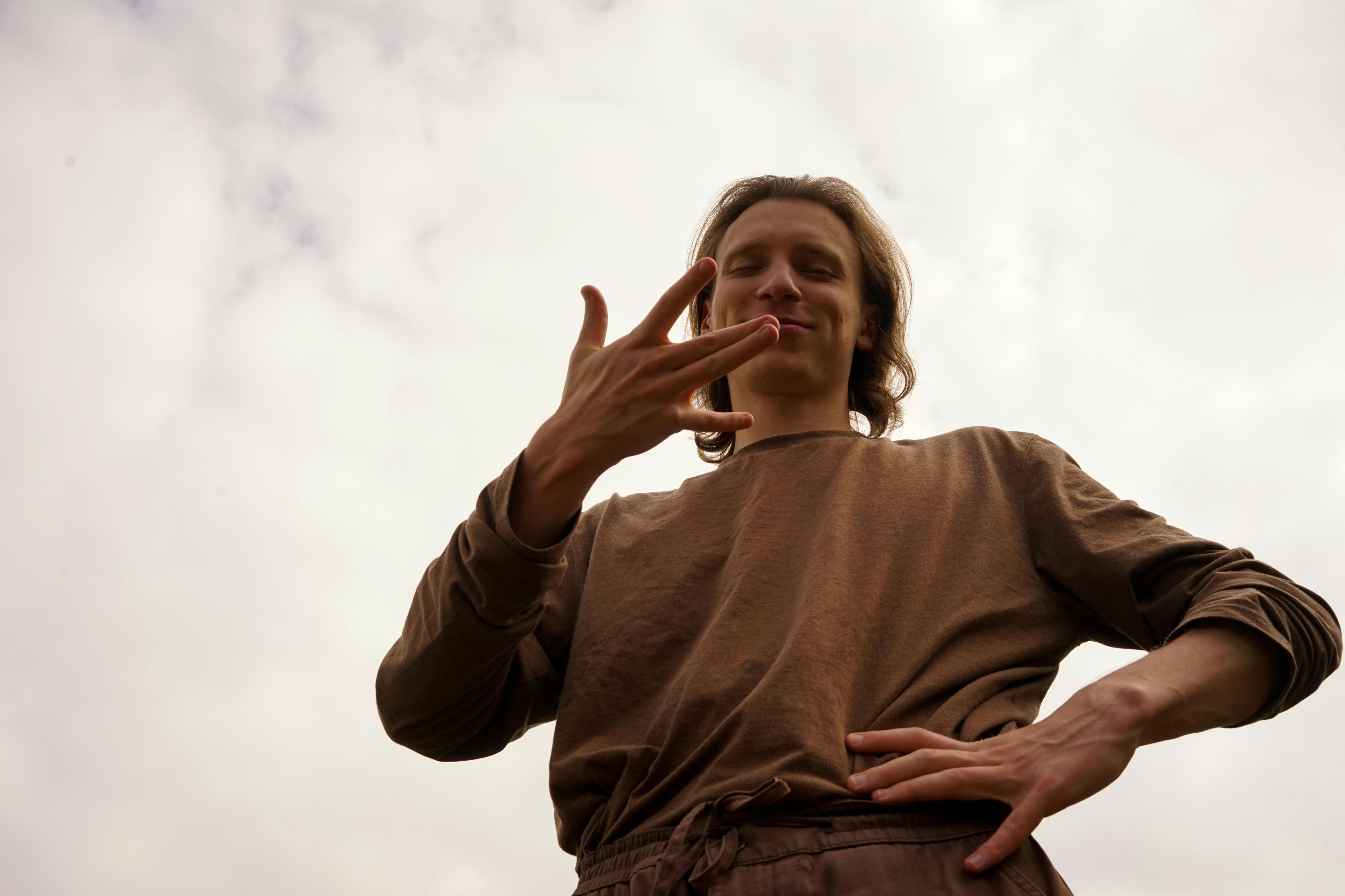 casual man gesturing under cloudy sky outdoors